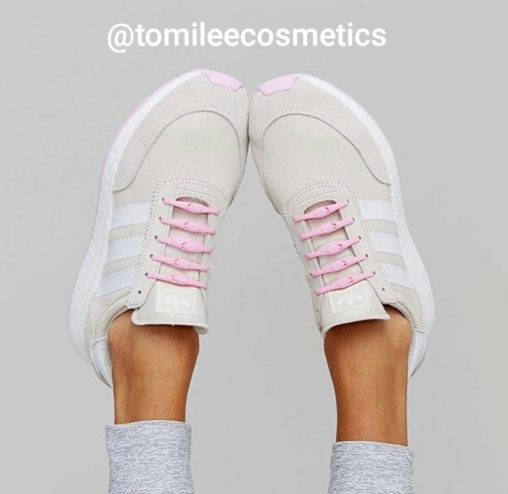 a woman is holding a pink tennis shoe 
